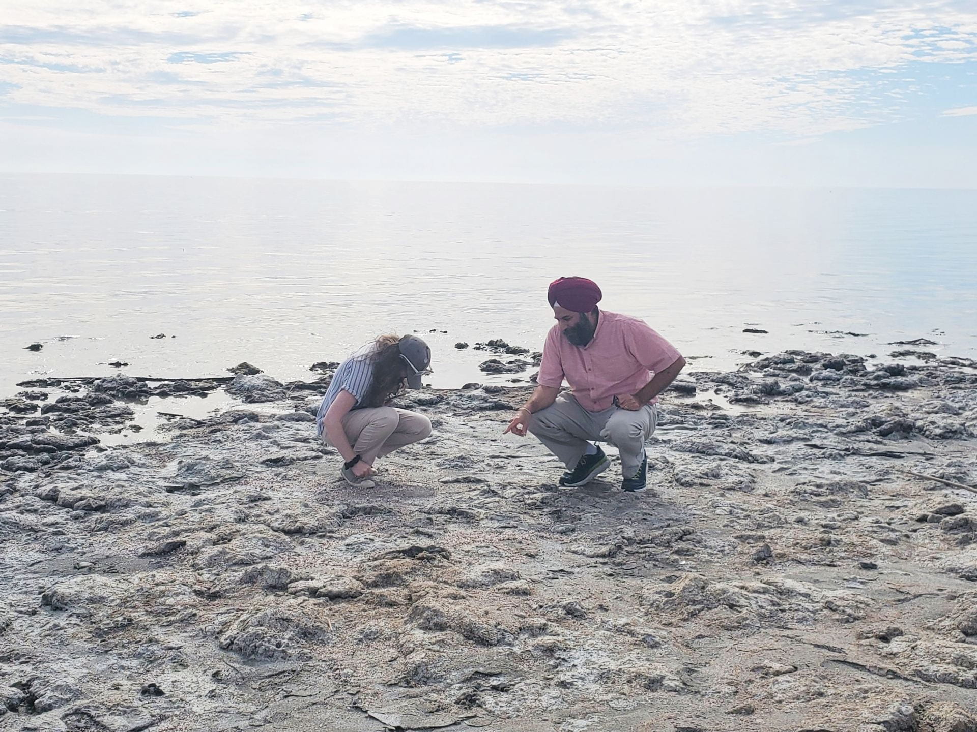 Two people examining a dried sea bed while discussing what they see.