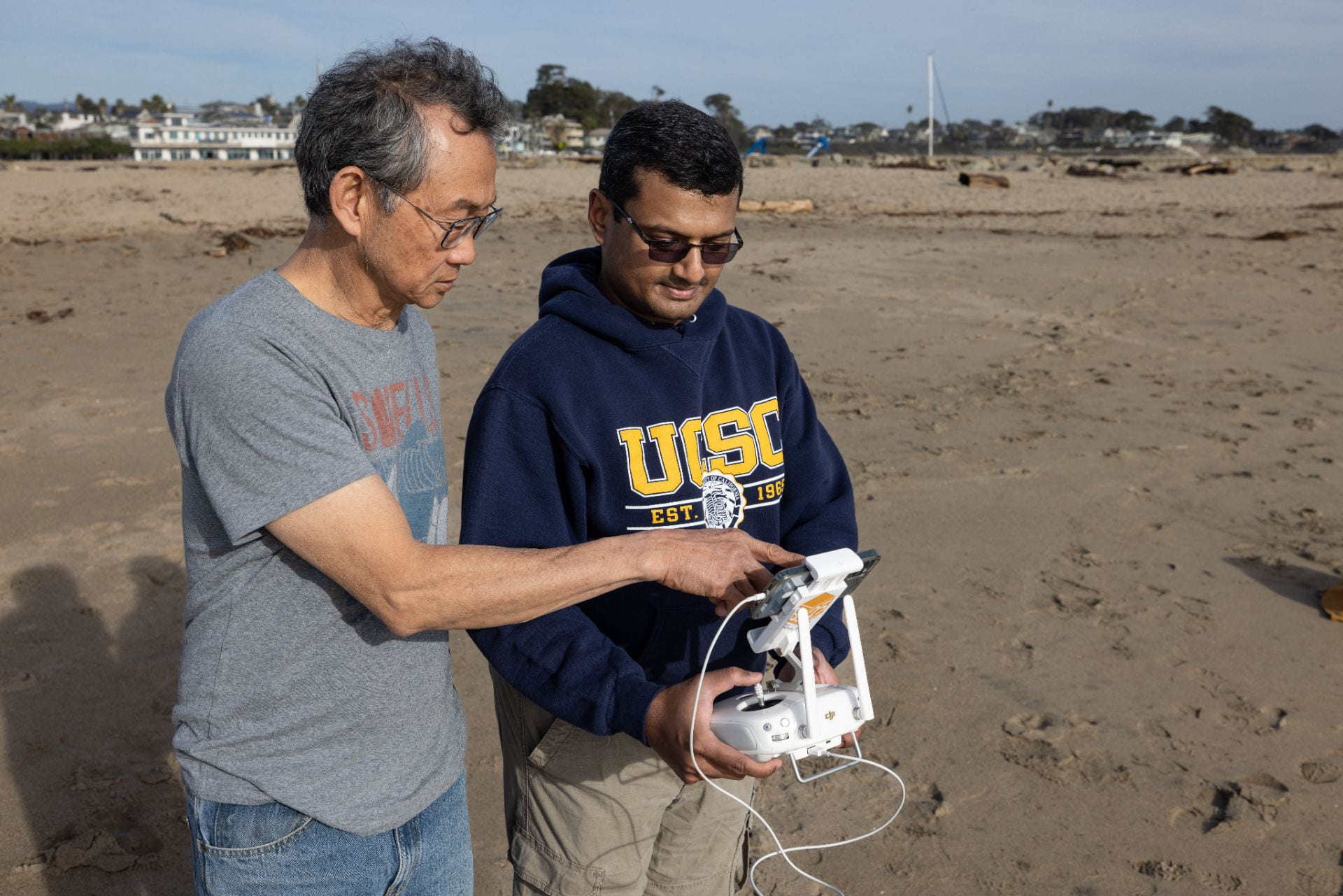 Two people on the beach learning to use a drone